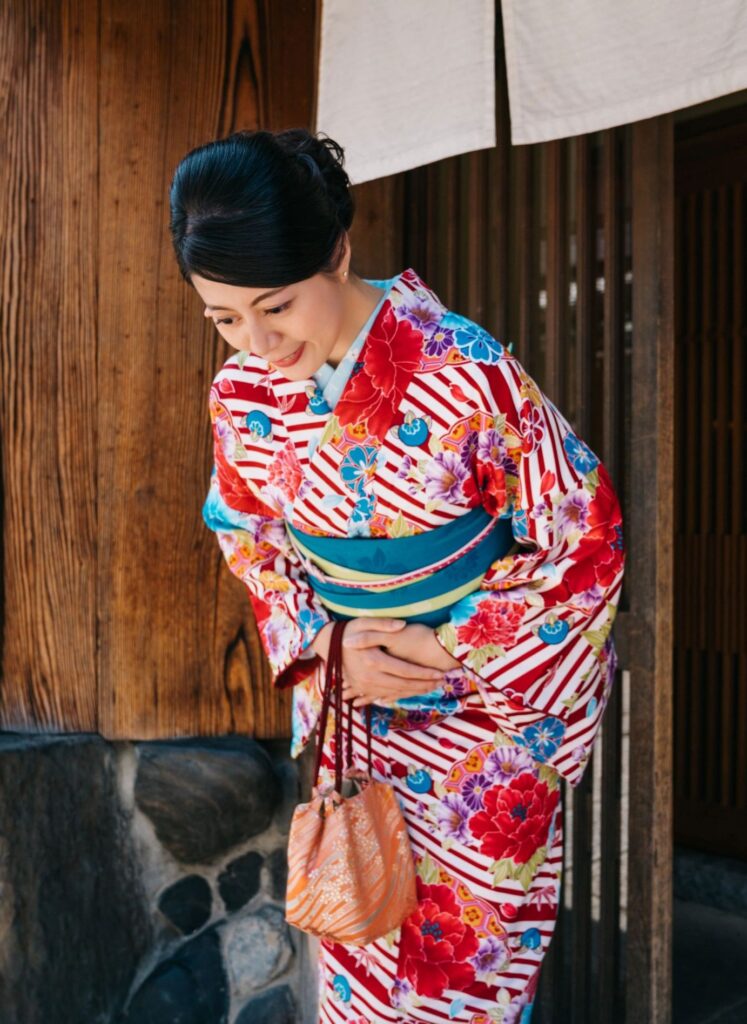 Frau in farbenfrohem Kimono vor einem traditionellen Holzhaus in Japan