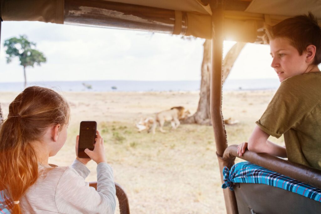 Kinder im offenen Safari-Fahrzeug fotografiert die Savanne in Afrika