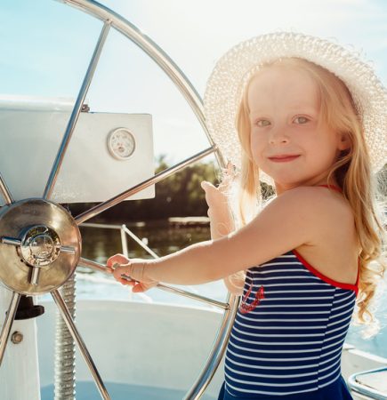 The children on board of sea yacht The children on board of sea yacht drinking orange juice. The teen or child girls against blue sky outdoor. Colorful clothes. Kids fashion, sunny summer, river and holidays concepts.